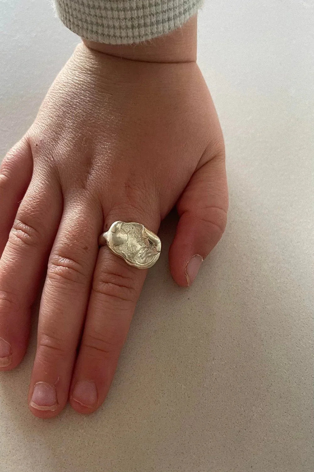 A gold fingerprint impression ring resting on a child’s hand, handcrafted in 18ct yellow gold, symbolizing love, connection, and timeless memories.