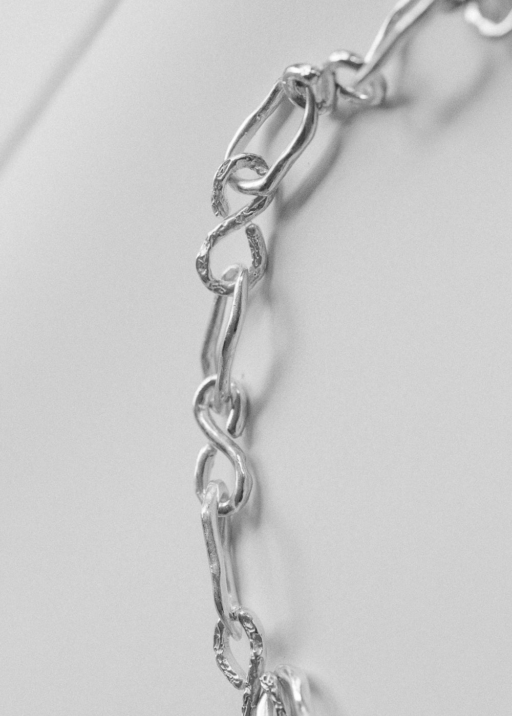 Close-up of handcrafted sterling silver dog collar links, showing organic textures and chain design by RFL.